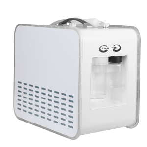 White compact appliance with a curved handle on top and a clear water bottle on the right, featuring a perforated vent panel on its side and a small circular knob.