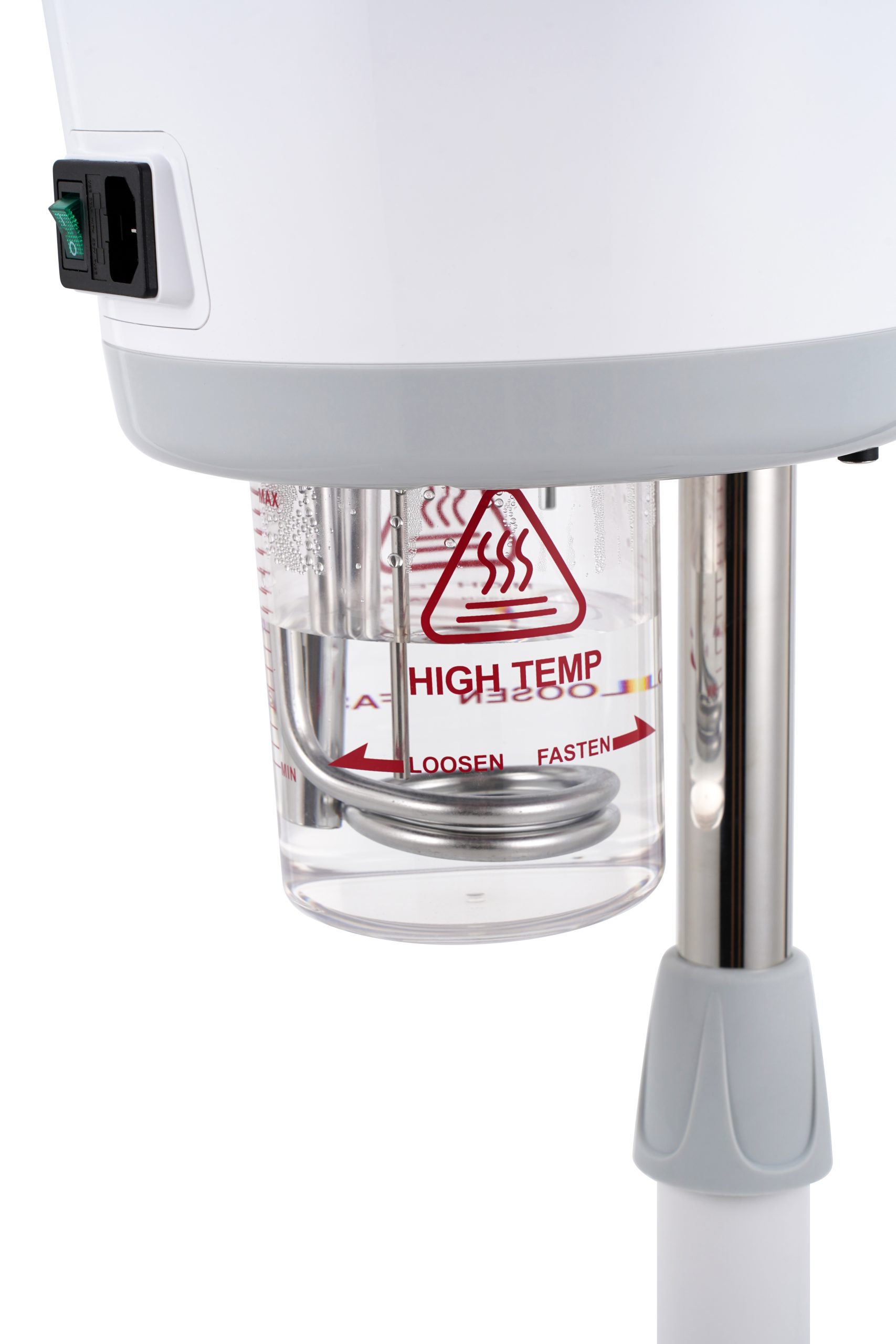 Close-up of a white appliance with a clear reservoir marked HIGH TEMP warning and red arrows, showing hot-water tubing and a gray handle/knob nearby.